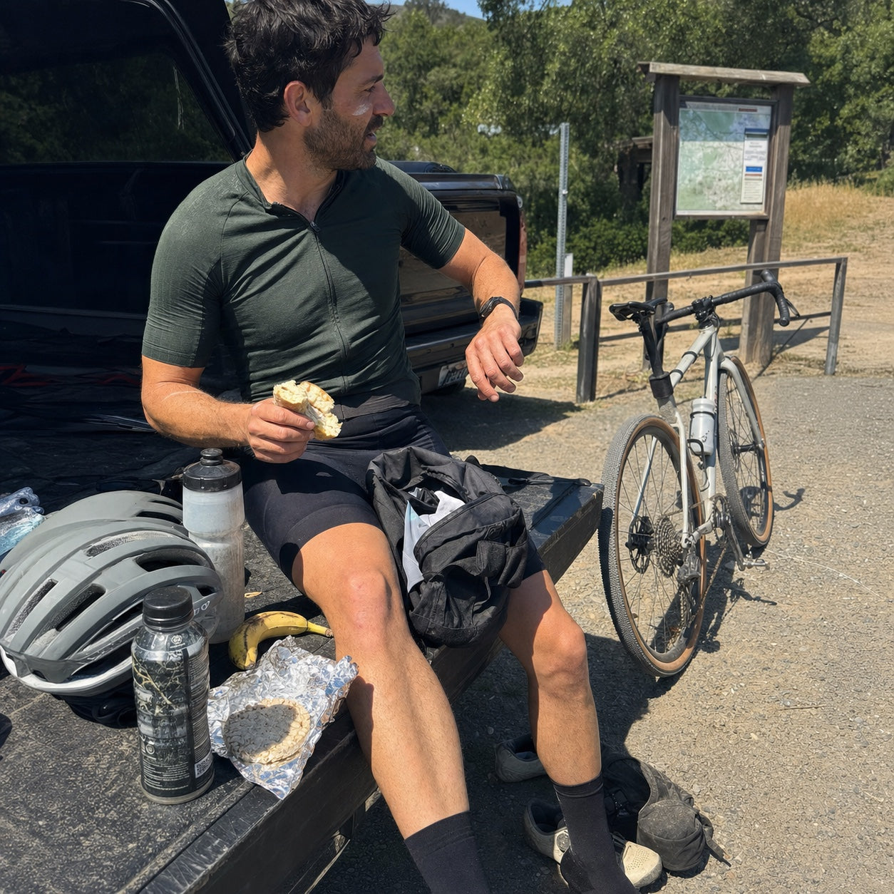 Amateur gravel cyclist eating a bagel at a local trailhead before a ride
